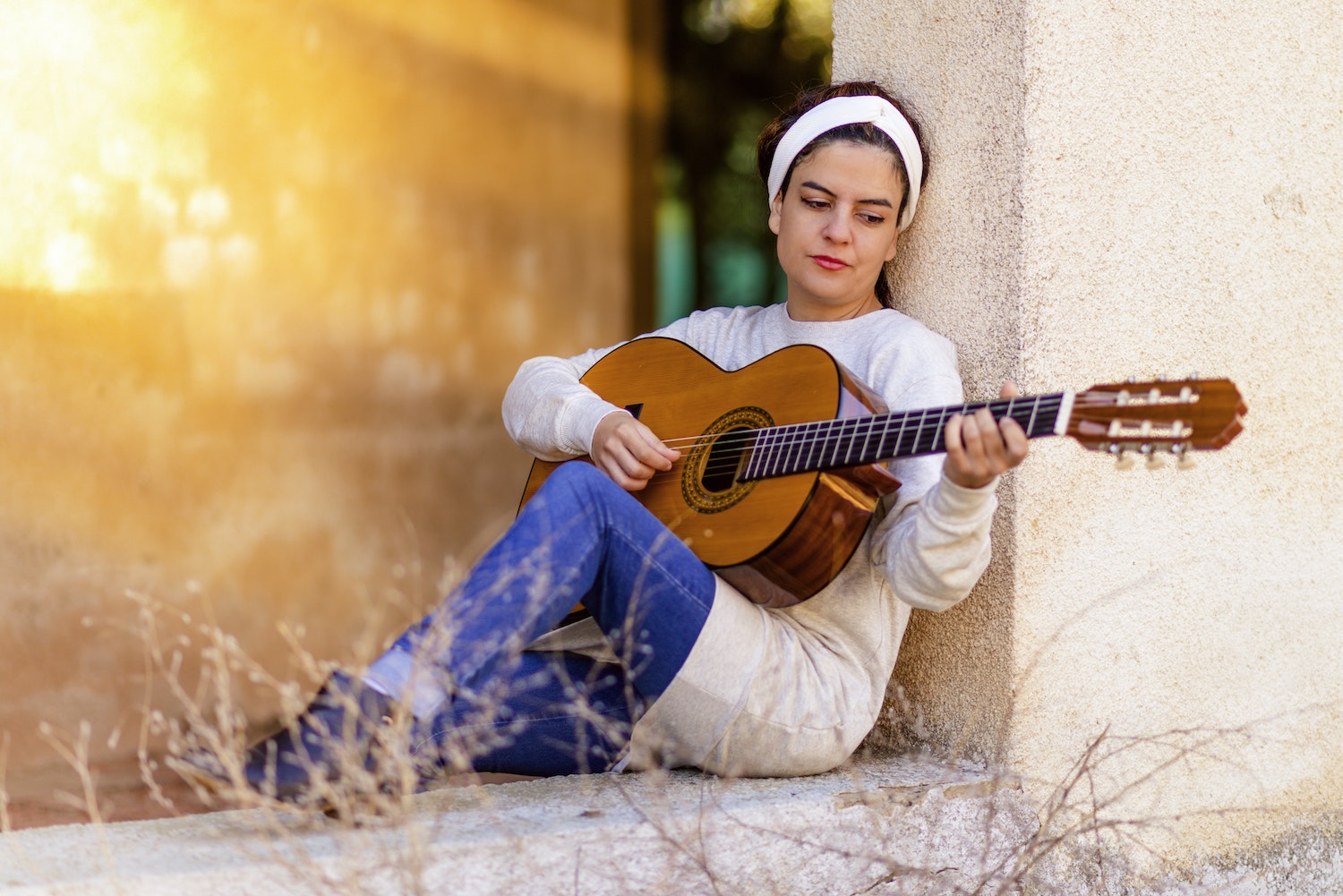 A woman playing the guitar has a look of contentment on her face.
