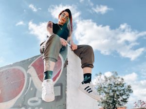 rebellious tattooed lady relaxing in skate park on sunny day. she feels confident in her self-identity.