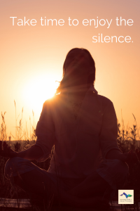 A silhouette of a person experiencing the benefits of silence by sitting on the ground in a meditation pose facing a sunset. Caption reads: "Take time to enjoy the silence."